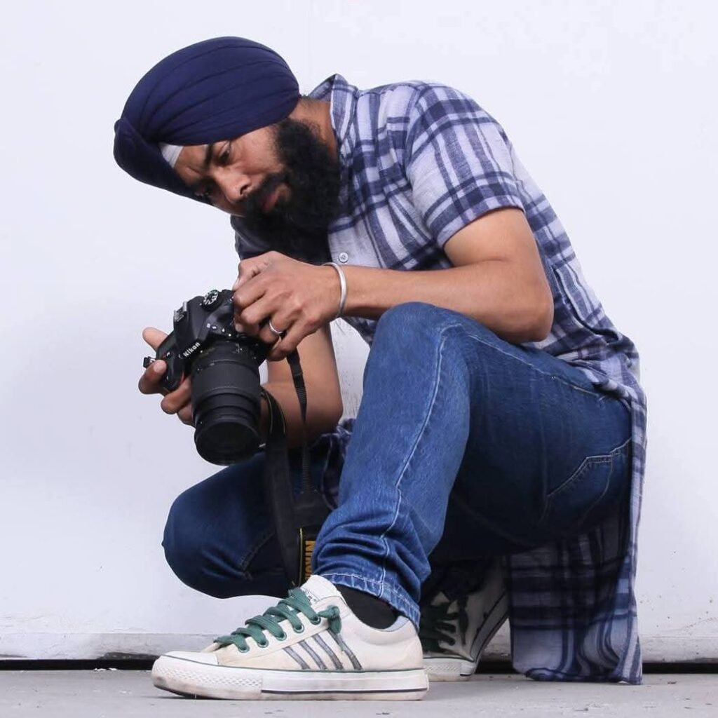 Hardev Singh holding a camera, looking contemplative, embodying his role as a photographer and observer.