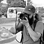 Monochrome image of Hardev Singh holding a camera, evoking a contemplative and timeless atmosphere.