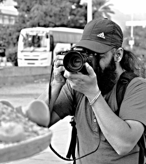 Monochrome image of Hardev Singh holding a camera, evoking a contemplative and timeless atmosphere.
